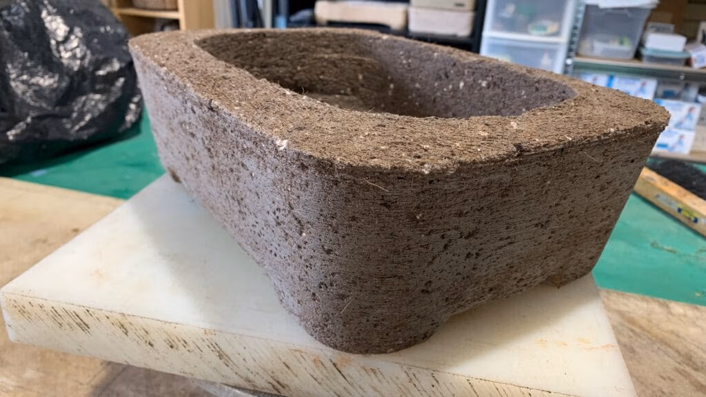 Fresh hypertufa planter just unmolded, showing the natural dark brown color of the wet cement and peat mixture.